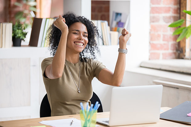 Woman sitting at desk celebrating 