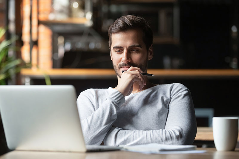 man thinking in front of laptop