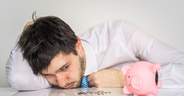 Young worried man has empty piggy money bank