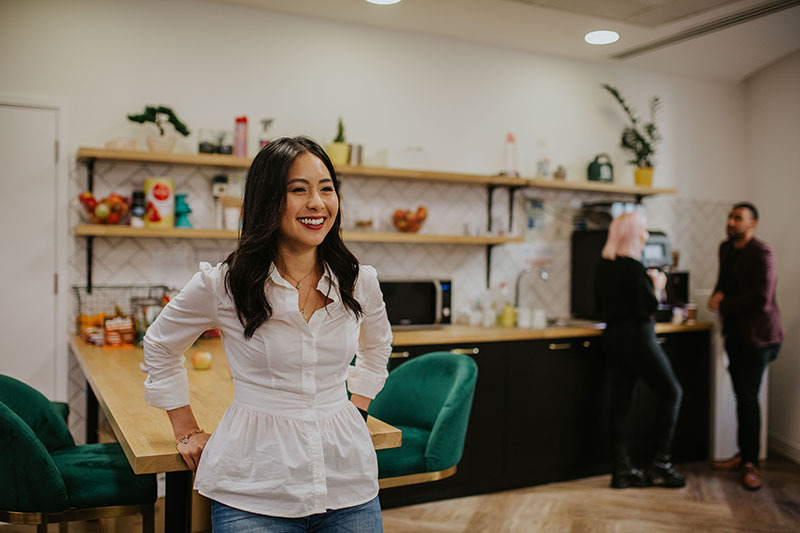 A satisfied employee smiling in the office kitchen