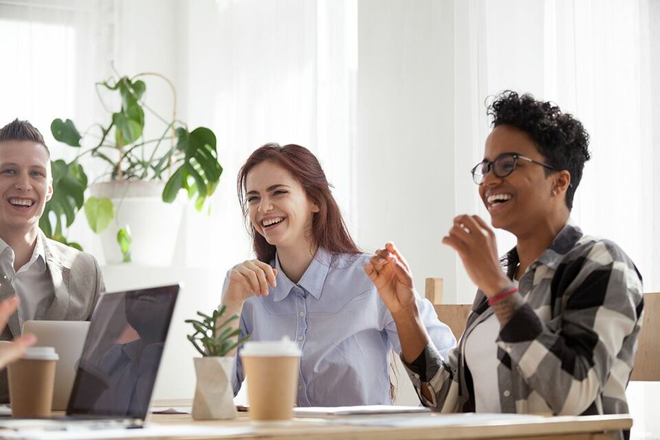 Employees smiling at a team meeting and enjoying their perks package