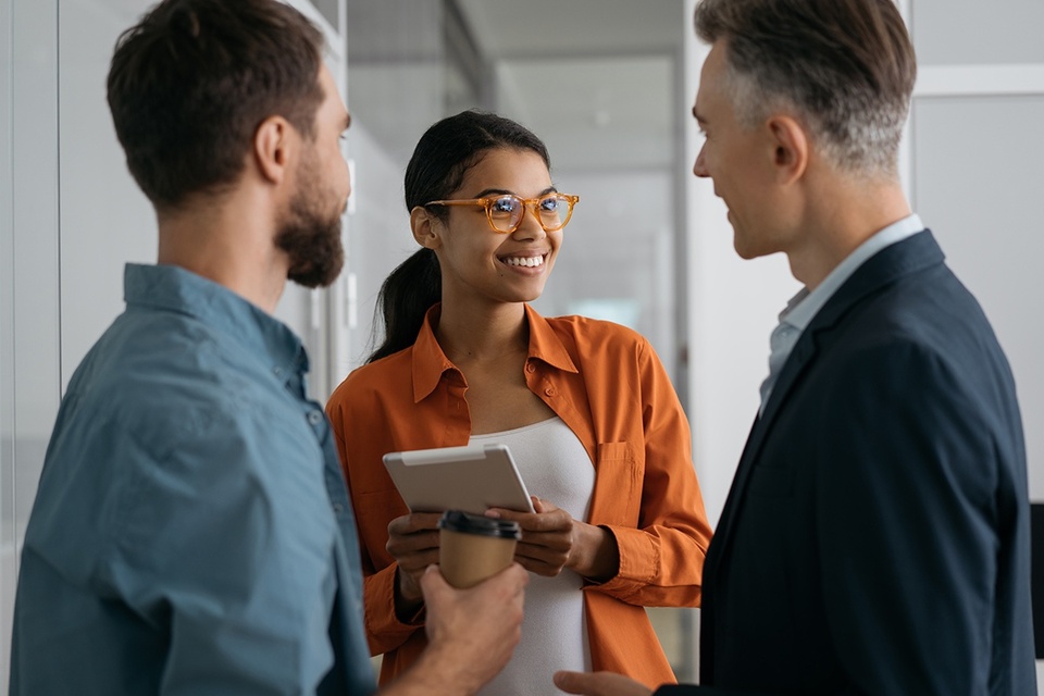 Three employees smiling and discussing reverse mentoring