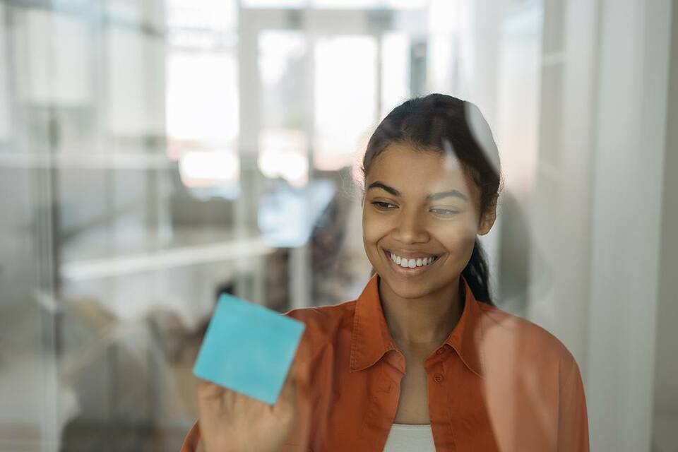 Female staff member placing a post-it note on the office window