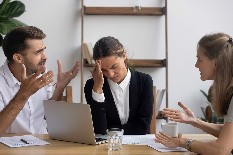 Annoyed employee rubbing her forehead during a tense meeting