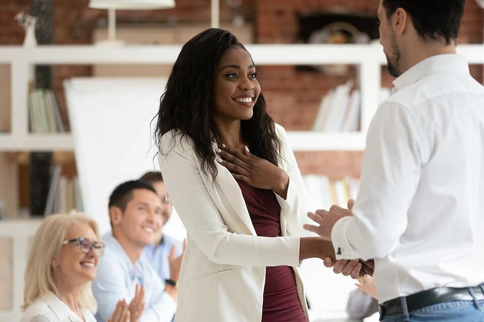 Employee smiling with a hand on her chest as she receives an award