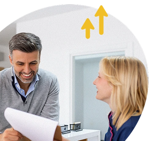 Two colleagues smiling during a discussion in an office, with upward arrows symbolising progress or growth.