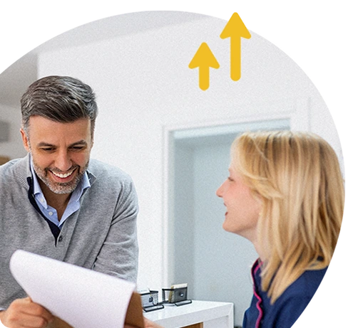Two colleagues smiling during a discussion in an office, with upward arrows symbolising progress or growth.