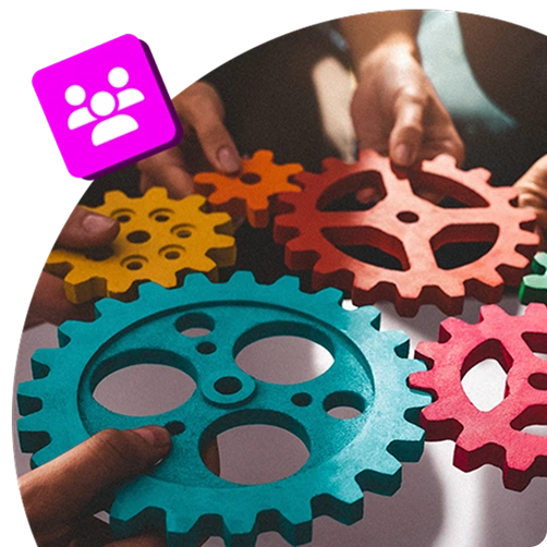 Hands holding colourful interlocking gears, representing teamwork, collaboration, and interconnected workplace roles.