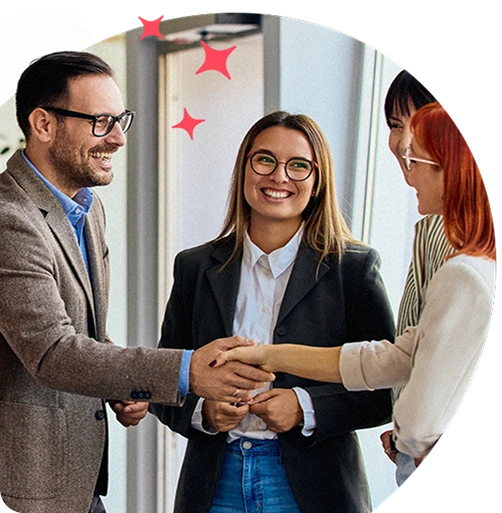 Group of colleagues smiling and shaking hands in an office, symbolising successful collaboration and positive workplace culture.