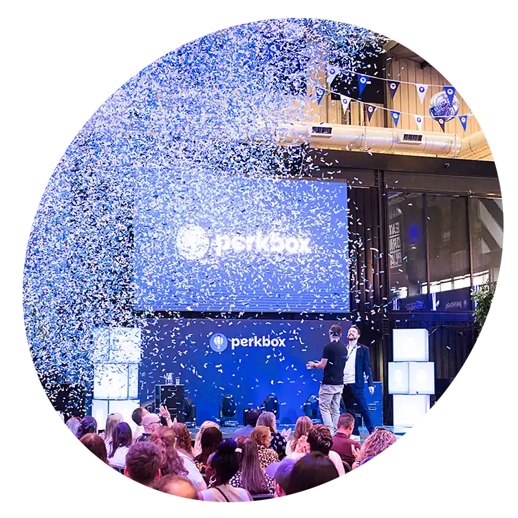 Confetti rains down at a packed Perkbox event, celebrating the company’s journey and impact on employee wellbeing.