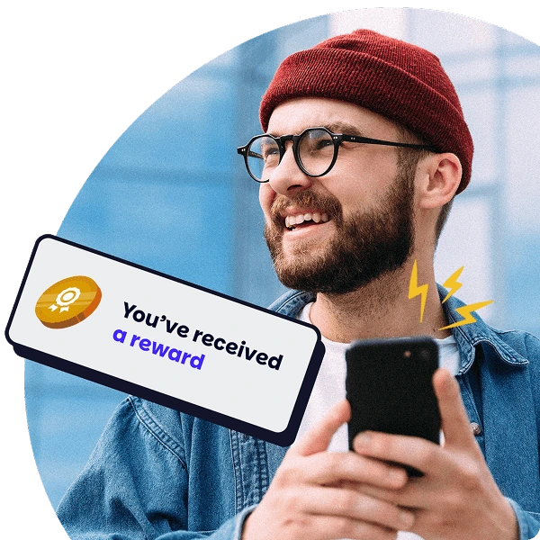 A happy employee smiles while holding a phone showing a reward notification, symbolising instant engagement through Perkbox.