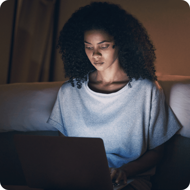 Person sitting alone at night, browsing on a laptop, symbolising an undervalued employee looking for a job change.