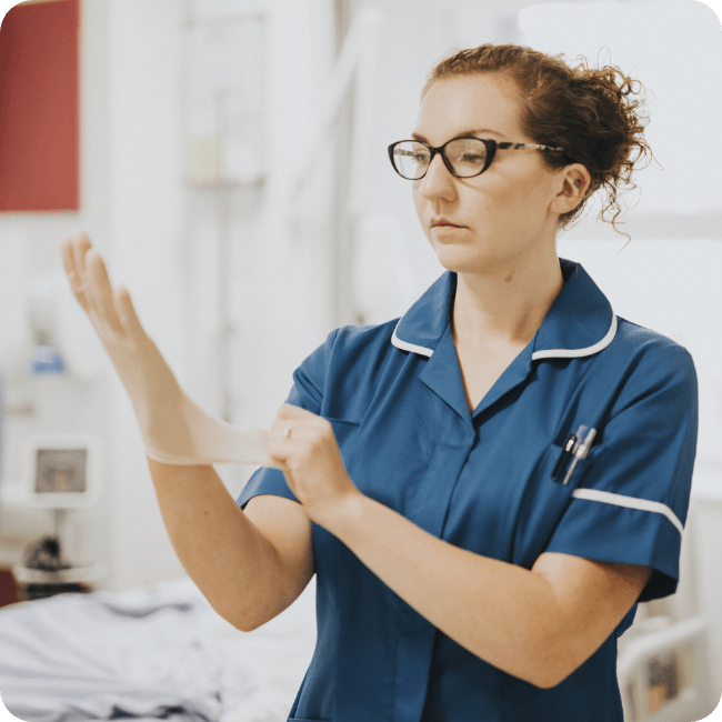 Healthcare worker in uniform putting on a glove in a clinical setting, representing frontline employees and the importance of feeling valued at work.