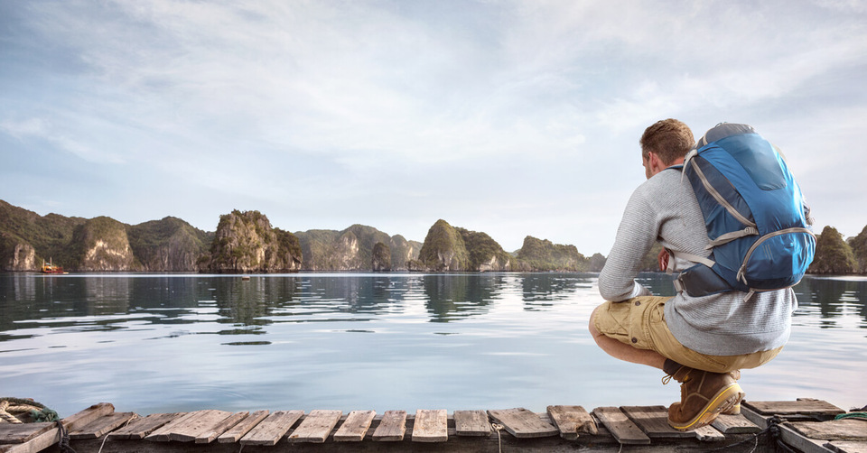 man looking into a lake while traveling