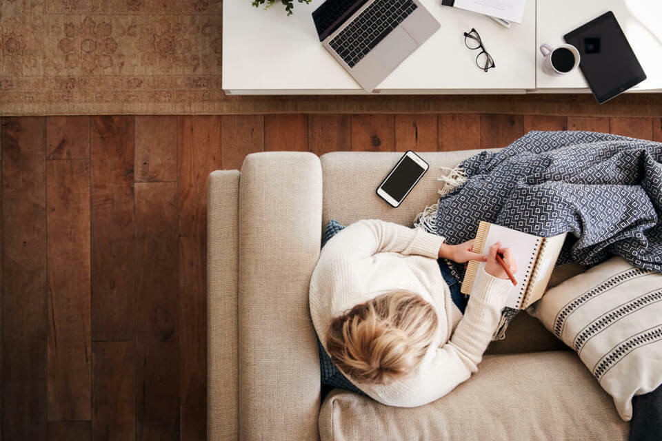 woman sat on sofa writing