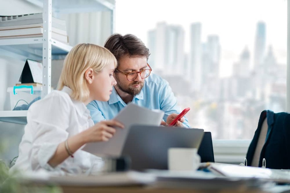 manager showing employee something on phone